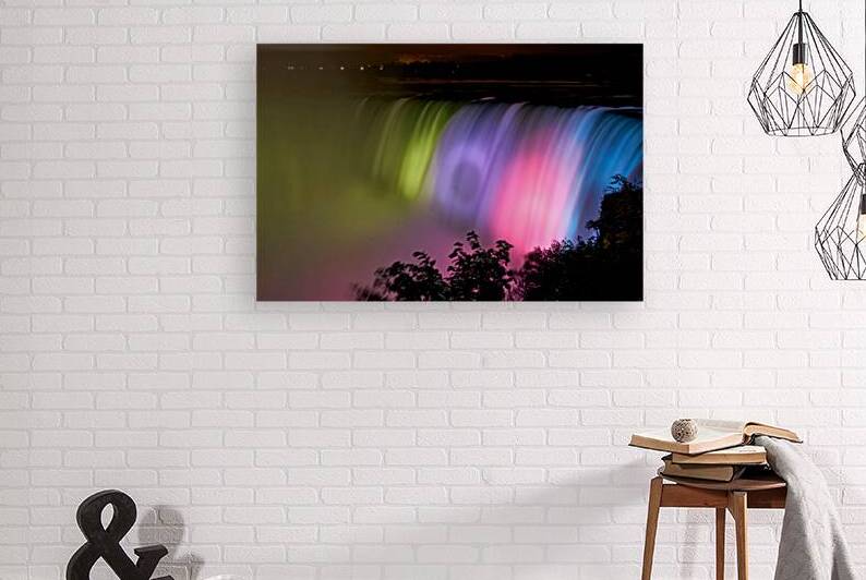 Niagara Falls illuminated with vibrant colors at night. by Marco Brivio