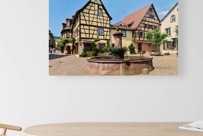 Tourists enjoy sunny day in Riquewihr Alsace near fountain and h by Marco Brivio