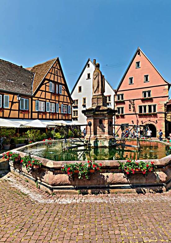 Visitors enjoy the fountain in Saint Leon Square in Eguisheim Al by Marco Brivio