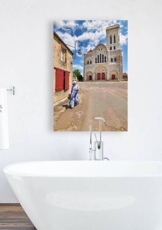 Nun walks by Vezelay Abbey in Bourgogne France during the day by Marco Brivio