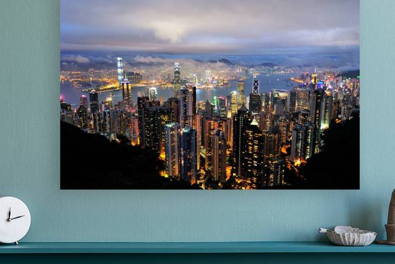 Hong Kong skyline with bright lights over harbor at night by Marco Brivio