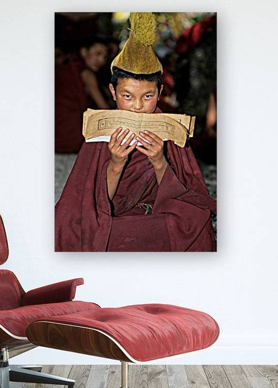 Young monk reads scripture in Tibet under natural light by Marco Brivio