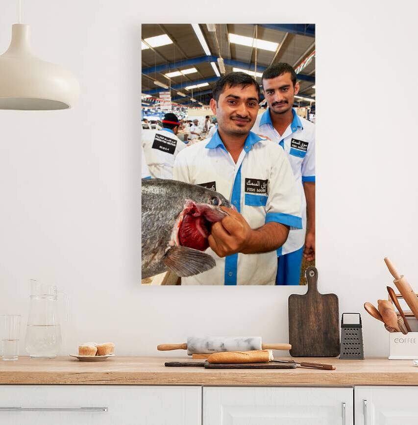 Smiling fishmongers hold fresh fish at market in Dubai UAE by Marco Brivio