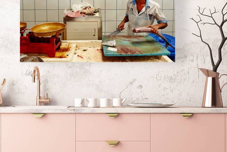Man cuts fish at a market stall in Dubai during daylight hours by Marco Brivio