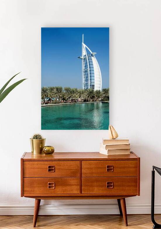Burj Al Arab hotel stands tall by the water with palm trees by Marco Brivio