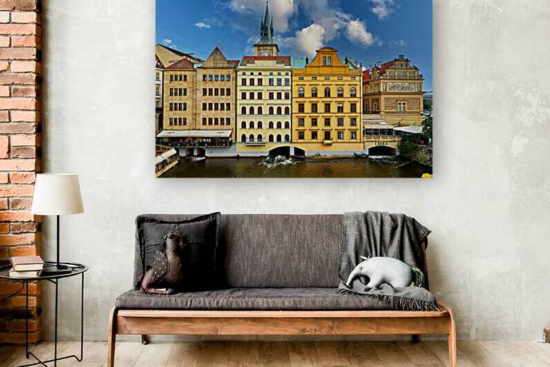 Historic Prague buildings and clock tower line a scenic river. by Marco Brivio