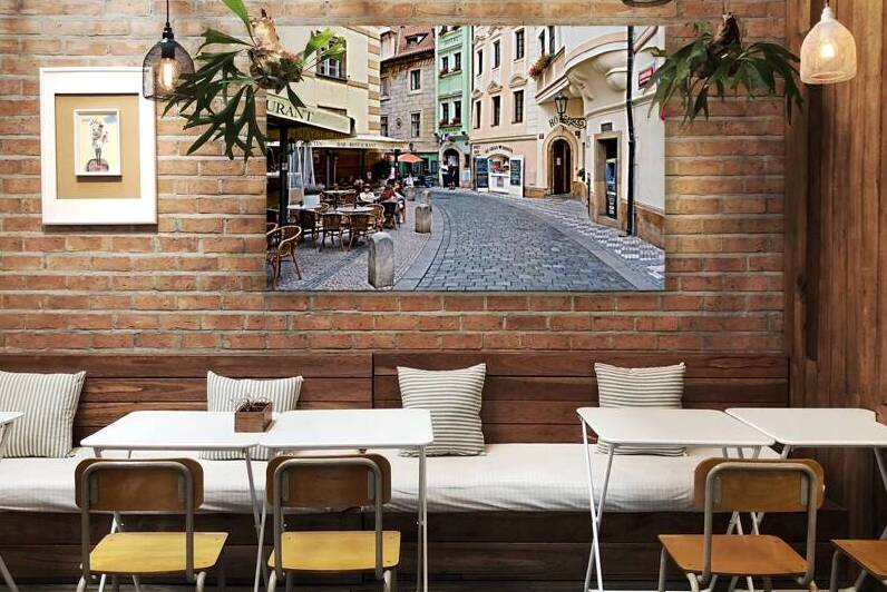 Cobblestone street in Prague with cafes shops and historic bui by Marco Brivio