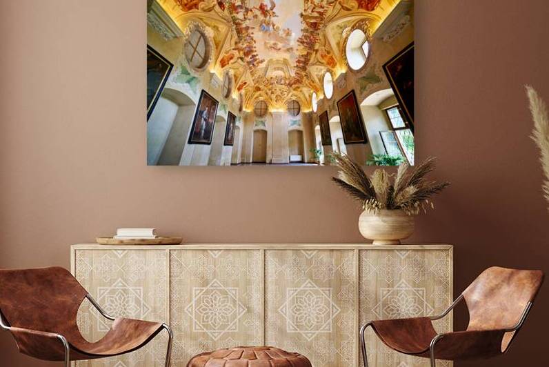 Grand hall with elaborate ceiling frescoes and framed portraits. by Marco Brivio