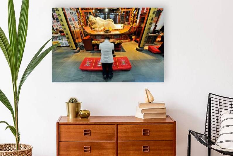 Worshipper kneels before Buddha statue in Shanghai temple by Marco Brivio