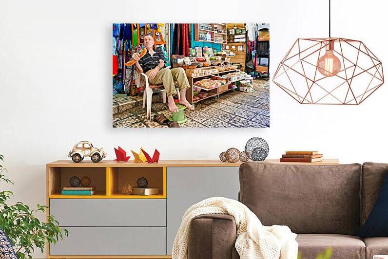 Old city shop in Jerusalem with man sitting and enjoying a snack by Marco Brivio