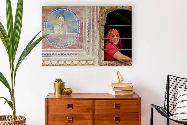 Woman smiles while looking out of a window in Mandawa Rajasthan by Marco Brivio