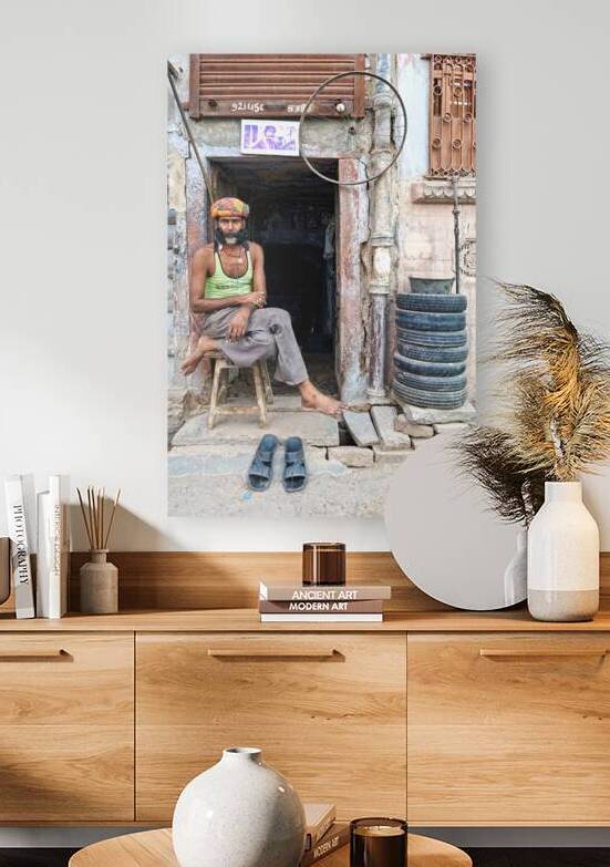 Man sitting outside a shop in Bikaner Rajasthan during the day by Marco Brivio