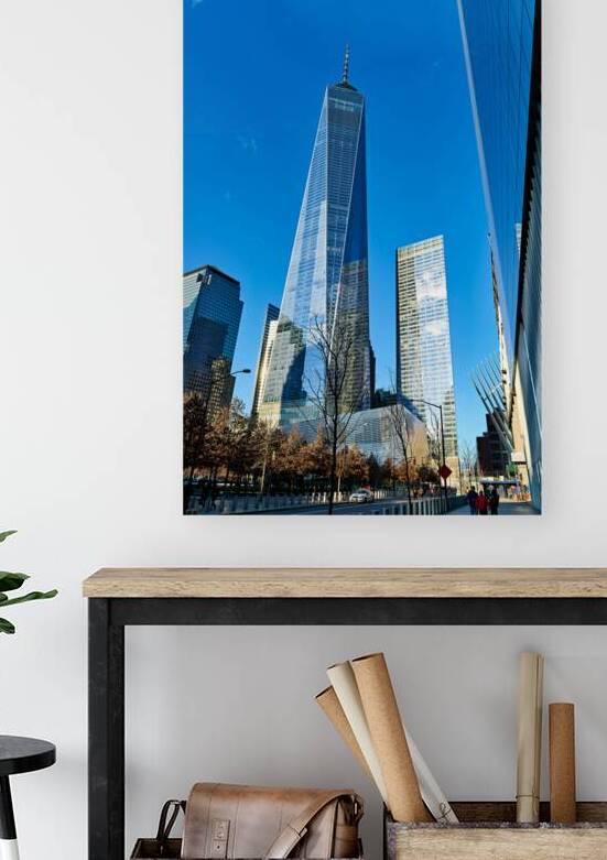 People walk near One World Trade Center with clear blue sky abov by Marco Brivio
