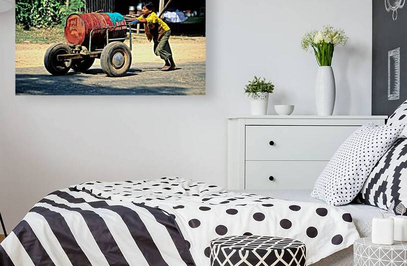 Boy pushes a cart down the street in Myanmar during the day by Marco Brivio