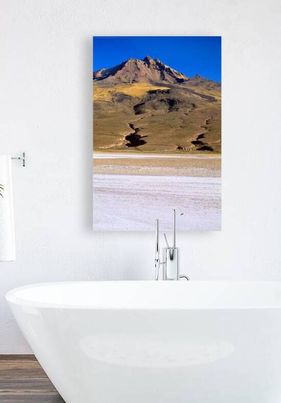 Mountain overlooks vast salt flat under clear blue sky. by Marco Brivio