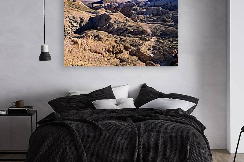 Hikers traverse a vast arid rocky desert landscape. by Marco Brivio