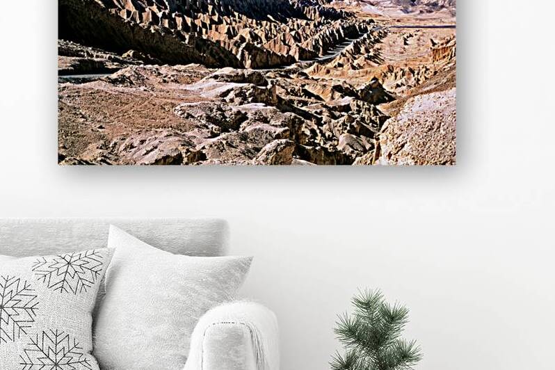 Eroded desert landscape with a road winding through mountains. by Marco Brivio