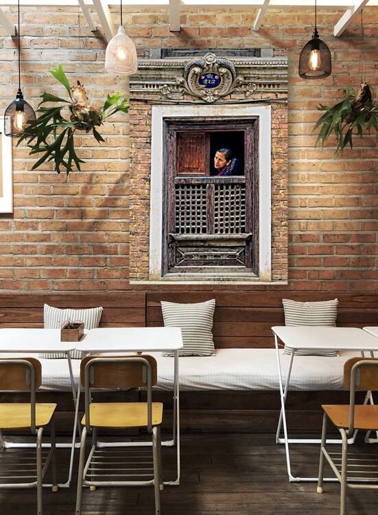 Woman in Kathmandu looks out from window in old building by Marco Brivio