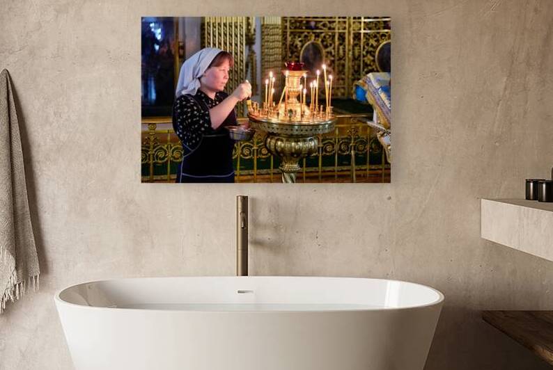 A woman lights candles in Transfiguration Cathedral in St by Marco Brivio