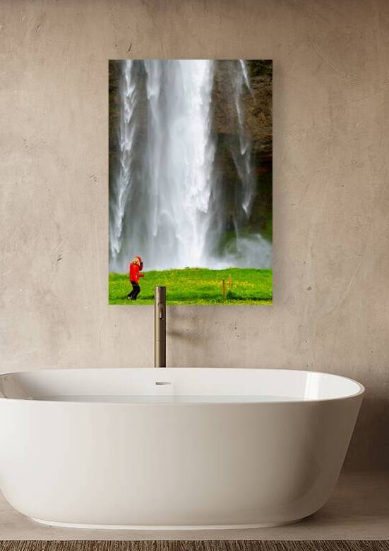 Woman walks near Seljalandsfoss waterfall in Iceland by Marco Brivio