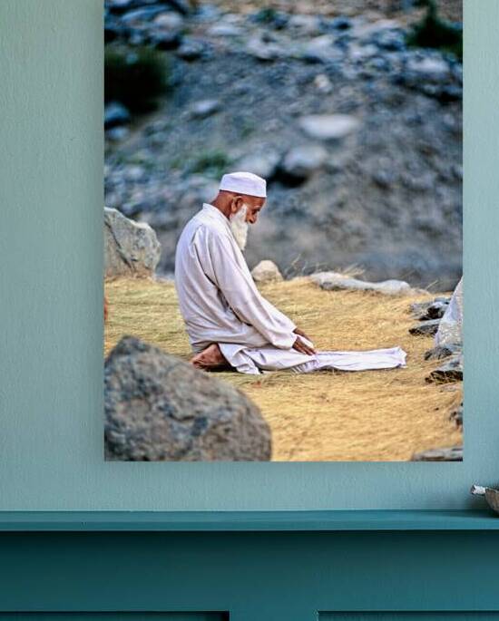 Elderly man in Pakistan sitting and praying on the ground by Marco Brivio