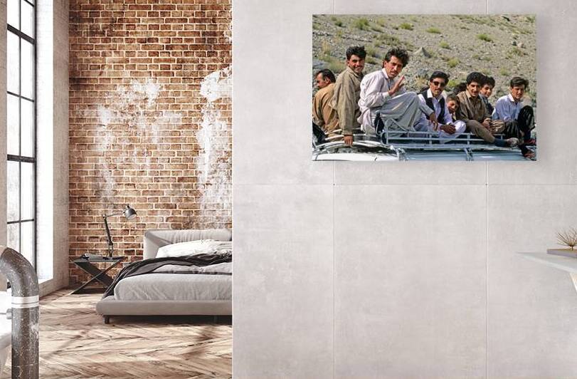 Group traveling on top of a van in Pakistans mountains by Marco Brivio