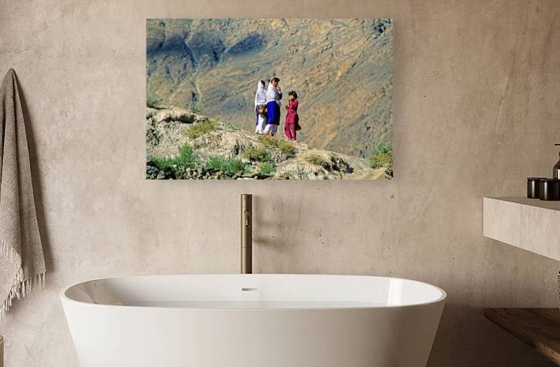 Women walk on hillside in Pakistan with mountains in view by Marco Brivio