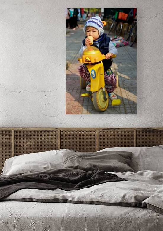 Child enjoys snack while riding tricycle in Hanoi streets by Marco Brivio