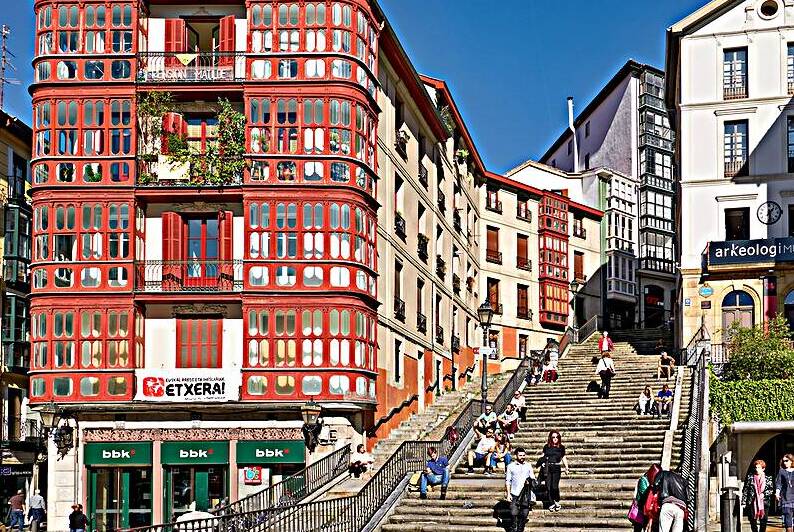 Stairs and buildings in downtown Bilbao Spain during the day by Marco Brivio