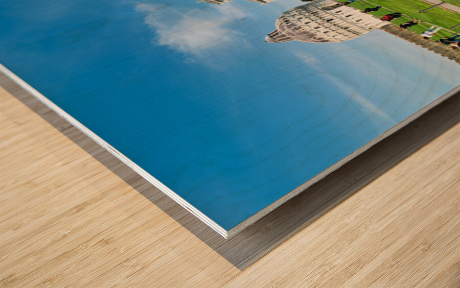 People walk in Piazza dei Miracoli admiring the Baptistry and Cathedral in Pisa. The sun shines on the historic buildings and green grass. Wood print